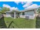 Back of house view with covered patio, green lawn, landscaping and central air conditioning unit at 1453 Otten St, Clearwater, FL 33755