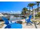 Waterfront backyard featuring boat dock, blue Adirondack chairs, and lush palm trees, perfect for relaxing at 1827 Venetian Point Dr, Clearwater, FL 33755