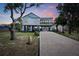 Beautifully elevated coastal home featuring a brick paved driveway, multiple balconies, and professionally landscaped yard at 1827 Venetian Point Dr, Clearwater, FL 33755
