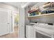 Modern laundry room with washer and dryer and storage shelves; bathroom located behind folding doors at 1827 Venetian Point Dr, Clearwater, FL 33755