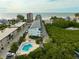 An aerial view of a community featuring well-maintained condos, pool, and lush greenery near the water at 19727 Gulf Blvd # 207, Indian Shores, FL 33785