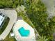 An aerial view of a pool with lounge chairs surrounded by vibrant greenery and a nearby canal at 19727 Gulf Blvd # 207, Indian Shores, FL 33785