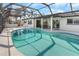 A beautiful screened-in pool with clear water, a covered lanai, and palm trees in the background at 200 98Th Ne Ave, St Petersburg, FL 33702