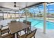A covered lanai with outdoor seating, ceiling fan overlooking the in-ground pool, and a canal view at 200 98Th Ne Ave, St Petersburg, FL 33702