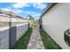A side yard walkway leads towards a swimming pool under bright blue skies at 200 98Th Ne Ave, St Petersburg, FL 33702