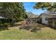 Spacious backyard with lush green grass, mature trees, and a screened-in pool area at 2029 Winding Oaks Dr, Palm Harbor, FL 34683