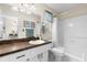 Cozy bathroom with a shower-tub combo, sink with dark countertop, and white cabinetry at 2029 Winding Oaks Dr, Palm Harbor, FL 34683