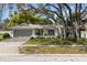 Charming single-story home with well-maintained landscaping and a two-car garage nestled under mature trees at 2029 Winding Oaks Dr, Palm Harbor, FL 34683