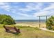Scenic beach view featuring a wooden bench, clear waters, and lush greenery at 224 Ontario Ave, Crystal Beach, FL 34681
