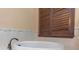 Elegant bathroom featuring a white bathtub with bronze fixtures and stylish wood shuttered window at 2630 Grand Lakeside Dr, Palm Harbor, FL 34684