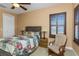 This bedroom features a patchwork quilt on the bed, shuttered windows, ceiling fan, and a rocking chair at 2630 Grand Lakeside Dr, Palm Harbor, FL 34684