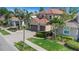 Charming two-story home with a well-manicured lawn, mature palm trees, and a beautiful brick driveway at 2630 Grand Lakeside Dr, Palm Harbor, FL 34684
