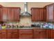Spacious kitchen with brown cabinets, stainless steel vent hood, and granite countertops at 2630 Grand Lakeside Dr, Palm Harbor, FL 34684
