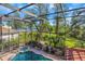 Screened-in pool with hot tub overlooking a serene lake and beautifully landscaped backyard at 2630 Grand Lakeside Dr, Palm Harbor, FL 34684