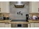 Close-up of modern cooktop with pot filler and stainless steel vent hood at 29844 Baywood Ln, Wesley Chapel, FL 33543