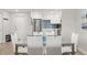 Dining area featuring a modern glass table, white chairs, and an adjacent renovated kitchen at 4681 1St Ne St # 306, St Petersburg, FL 33703