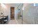 Modern bathroom featuring a glass shower with natural-tone stone tiling and a double vanity at 5128 Slate Hue Pl, Apollo Beach, FL 33572