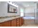 Bright bathroom featuring double vanity with granite countertop, a large mirror, and a bathtub at 513 Tweed Ave, Seffner, FL 33584