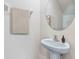 Close-up of a bathroom with a pedestal sink, round mirror, towel bar and neutral wall color creating a clean and simple space at 5231 Salt Marsh Rd, Wimauma, FL 33598