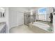 Spa-like bathroom featuring a soaking tub, a glass enclosed shower, and plantation shutters at 5239 Admiral Pointe Dr, Apollo Beach, FL 33572