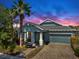 Charming single-Gathering home featuring a well-kept lawn, palm trees, and paved driveway at sunset at 5239 Admiral Pointe Dr, Apollo Beach, FL 33572