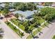 Aerial view of a charming two-story yellow house with a grey roof surrounded by lush greenery and palm trees at 556 21St Ne Ave, St Petersburg, FL 33704