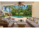 Covered patio with comfortable seating overlooking the pool, lush greenery, and outdoor entertainment area at 556 21St Ne Ave, St Petersburg, FL 33704