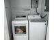 Bright laundry room featuring a new white washer and dryer set with a metal shelf and tankless water heater at 633 47Th N Ave, St Petersburg, FL 33703