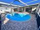 Caged in-ground pool area with outdoor grill and pavers at 7114 Parrot Dr, Port Richey, FL 34668