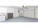 Garage with utility sink, white walls, gray epoxy floors, and a roll-up garage door at 7336 Cherry Laurel Dr, Port Richey, FL 34668