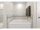Bathroom featuring a soaking tub with decorative tile surround and modern fixtures at 7513 S Sherrill St, Tampa, FL 33616