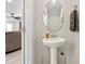 Half-bathroom with pedestal sink and oval mirror at 7513 S Sherrill St, Tampa, FL 33616