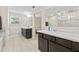 Bathroom with double vanities, dark cabinetry, and separate shower and tub at 7513 S Sherrill St, Tampa, FL 33616