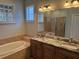 Bathroom featuring a soaking tub, glass shower and a double vanity with granite countertop at 832 King Leon Way, Sun City Center, FL 33573