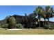 The backyard exterior is adorned with lush greenery, complemented by swaying palm trees and manicured lawn at 832 King Leon Way, Sun City Center, FL 33573