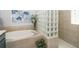 Luxurious bathroom featuring soaking tub with elegant tile surround and glass block accents, alongside decorative plants and wall art at 8376 Golden Prairie Dr, Tampa, FL 33647
