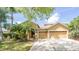 Charming home with a well-manicured lawn, mature trees, and a spacious driveway leading to a three-car garage at 8376 Golden Prairie Dr, Tampa, FL 33647