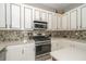 Modern kitchen with stainless steel appliances, stone backsplash, white cabinets, and ample countertop space at 8376 Golden Prairie Dr, Tampa, FL 33647
