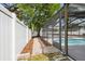 A backyard featuring a screened-in pool, a brick walkway, a privacy fence, and mature trees at 930 Balsamina Dr, Brandon, FL 33510