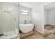 Bathroom with a modern glass shower, freestanding tub, and wood-look flooring at 930 Balsamina Dr, Brandon, FL 33510