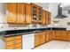Traditional-style kitchen with wooden cabinets, black countertops, white appliances, and tile backsplash with decorative accents at 5202 Lydia Ct, Spring Hill, FL 34608