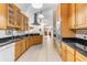 Open kitchen layout with wooden cabinets, black countertops, stainless steel appliances, and a view of the living space at 5202 Lydia Ct, Spring Hill, FL 34608