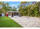 Spacious backyard with artificial turf, paved patio, fire pit, outdoor lighting, and a hot tub at 1136 Serpentine S Dr, St Petersburg, FL 33705