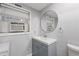 Clean bathroom with a gray vanity, a round mirror, and an air conditioning unit in the window at 1136 Serpentine S Dr, St Petersburg, FL 33705