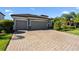 Luxury home featuring a three car garage, stone accents, and a paver driveway at 11412 Autumn Leaf Way, Bradenton, FL 34212