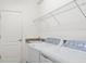 Bright laundry room with modern washer and dryer set and overhead shelving for optimal storage at 11412 Autumn Leaf Way, Bradenton, FL 34212