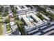 Expansive aerial view of an apartment complex featuring manicured green spaces, a central swimming pool, and ample parking at 1706 Belleair Forest Dr # 336, Belleair, FL 33756