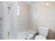 Bathroom featuring a tub with shower, tiled walls and a toilet at 1706 Belleair Forest Dr # 336, Belleair, FL 33756