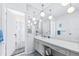 All-white bathroom featuring mirrored wall, decorative lighting, and a shower with a patterned curtain at 1706 Belleair Forest Dr # 336, Belleair, FL 33756
