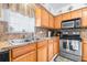 Traditional kitchen with stainless steel oven and microwave, light wood cabinets and double sinks at 1706 Belleair Forest Dr # 336, Belleair, FL 33756